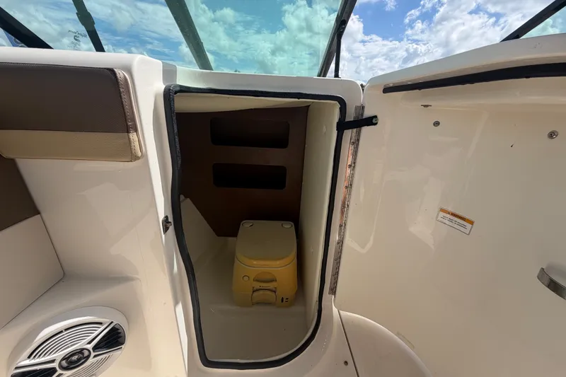 Slide: The Image of 2014 Sea Ray 240 Sundeck interior storage compartment with portable toilet under blue sky. - 27