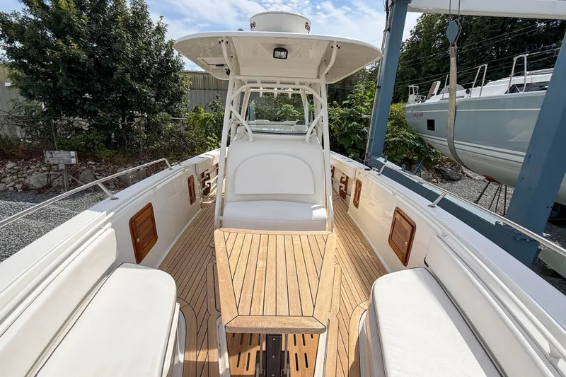 Slide: The Image of 2013 Boston Whaler 32 Justice boat interior with seating and wooden deck. - 19