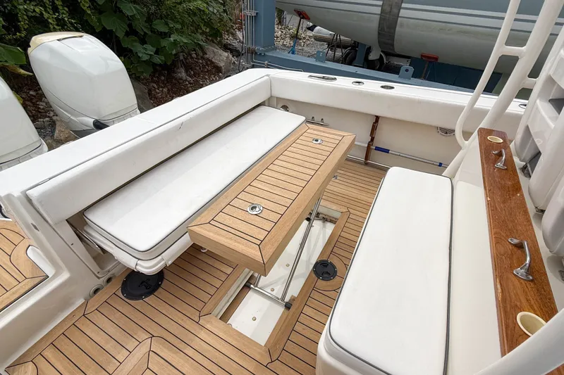 Slide: The Image of 2013 Boston Whaler 32 Justice boat interior with cushioned seating and wooden flooring. - 9