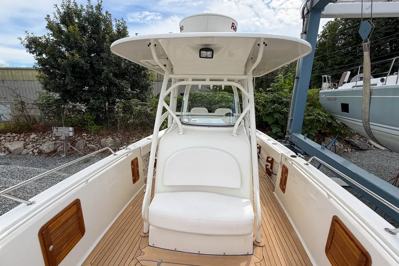 Slide: The Image of 2013 Boston Whaler 32 Justice boat interior with seating and canopy, docked outdoors. - 20