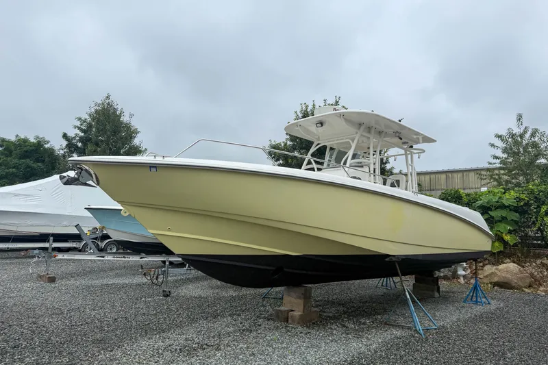The Image of 2013 Boston Whaler 32 Justice boat on stands, outdoor storage, overcast sky. - 0