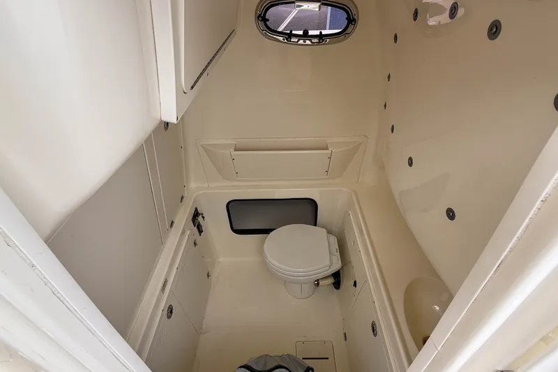Slide: The Image of Interior of 2013 Boston Whaler 32 Justice boat bathroom with compact toilet and storage. - 23