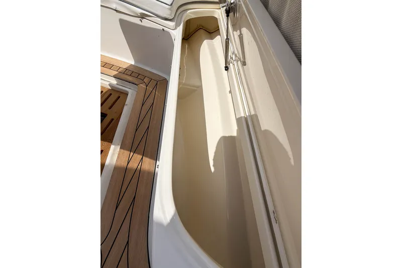 Slide: The Image of Interior view of a 2013 Boston Whaler 32 Justice boat, showcasing storage compartment and deck. - 29