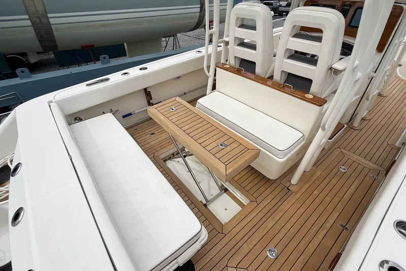 Slide: The Image of 2013 Boston Whaler 32 Justice boat interior with teak flooring and white seating. - 8