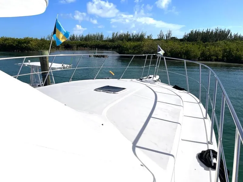 Slide: The Image of 1998 Navigator 53 yacht deck with flags, cruising through scenic waterway under blue sky. - 9