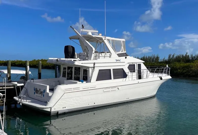 Slide: The Image of Navigator 53 yacht from 1998 docked in a serene marina under a clear blue sky. - 0