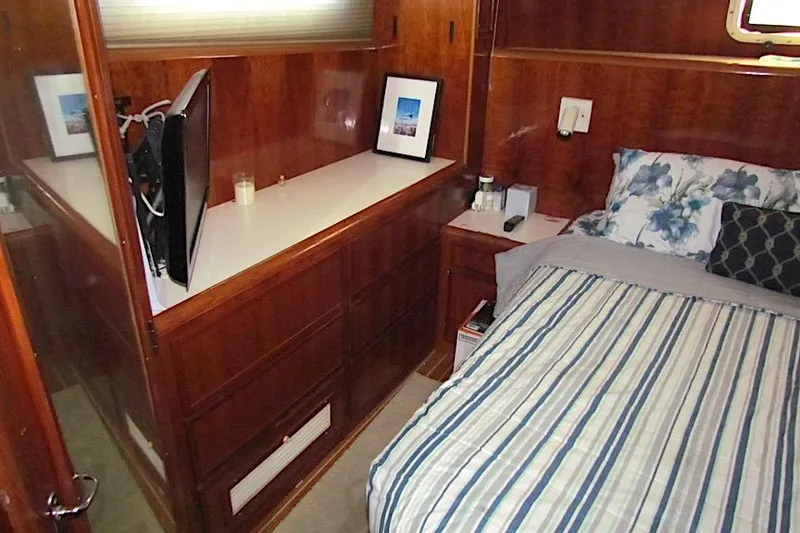 Slide: The Image of Cozy bedroom in 1992 Hatteras 40 Motor Yacht with wood paneling and striped bedding. - 18