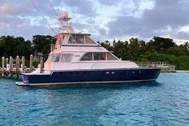 Slide: The Image of 1972 Hargrave 67 Motor Yacht on serene blue water, docked near lush greenery. - 0