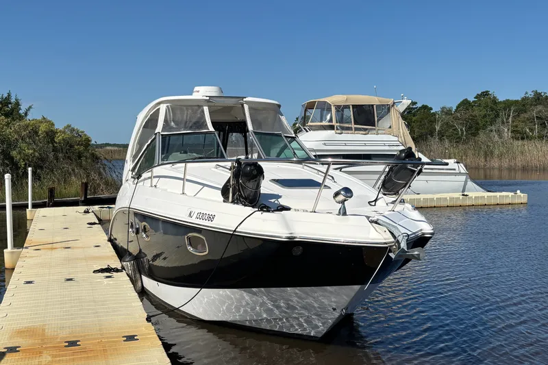 Slide: The Image of 2018 Chaparral 310 Signature boat docked on calm water under clear blue sky. - 2