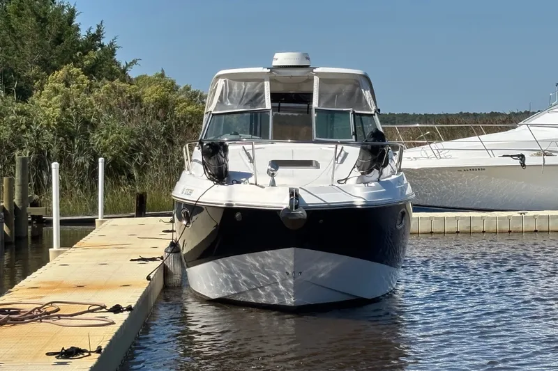 Slide: The Image of 2018 Chaparral 310 Signature boat docked at marina, surrounded by calm water and greenery. - 1