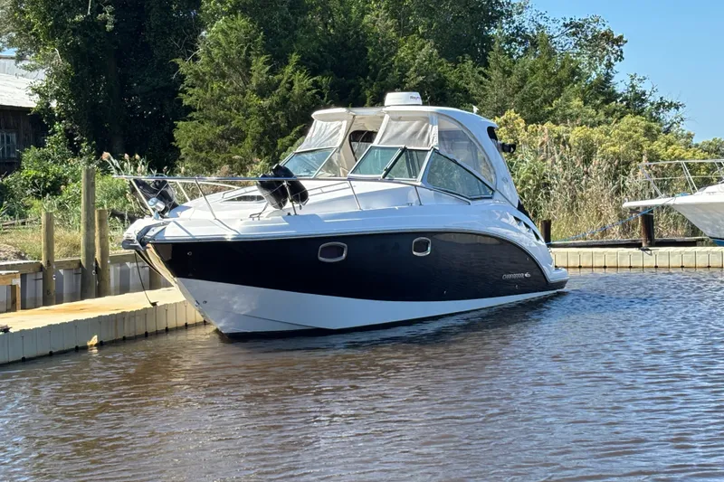 The Image of 2018 Chaparral 310 Signature boat docked on calm water, surrounded by greenery. - 0