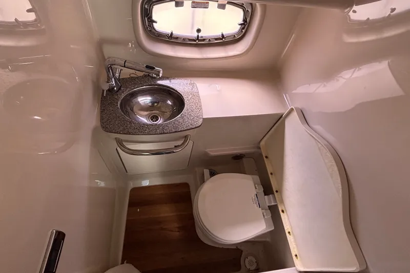 Slide: The Image of 2018 Chaparral 310 Signature boat bathroom with sink, toilet, and window. - 29
