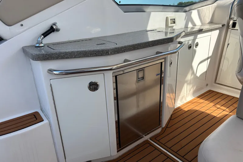Slide: The Image of 2018 Chaparral 310 Signature boat interior with kitchenette and wood flooring. - 25
