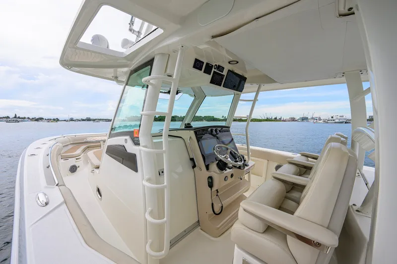 Slide: The Image of 2018 Boston Whaler 380 Outrage boat interior with helm and seating, on calm water. - 34