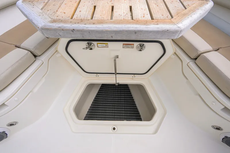 Slide: The Image of 2018 Boston Whaler 380 Outrage storage compartment with cushioned seating and wooden table. - 25