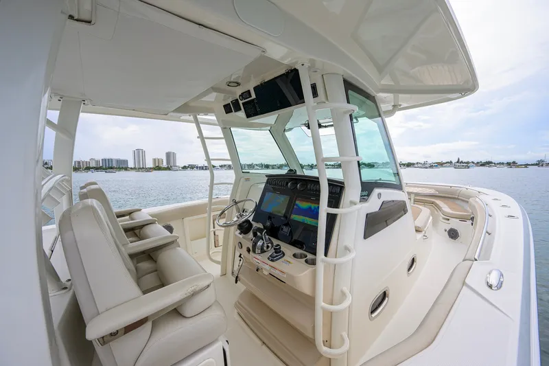 Slide: The Image of 2018 Boston Whaler 380 Outrage boat interior with helm and seating, overlooking waterfront skyline. - 13