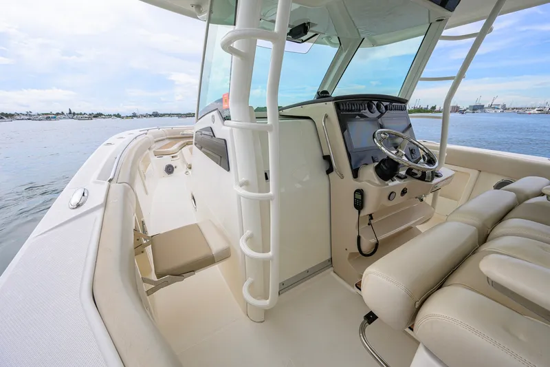 Slide: The Image of 2018 Boston Whaler 380 Outrage boat interior with helm and seating, docked on calm water. - 35