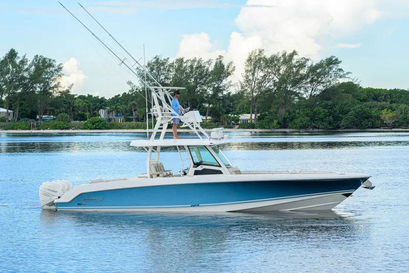 Slide: The Image of 2018 Boston Whaler 380 Outrage boat on calm water, surrounded by lush greenery. - 8