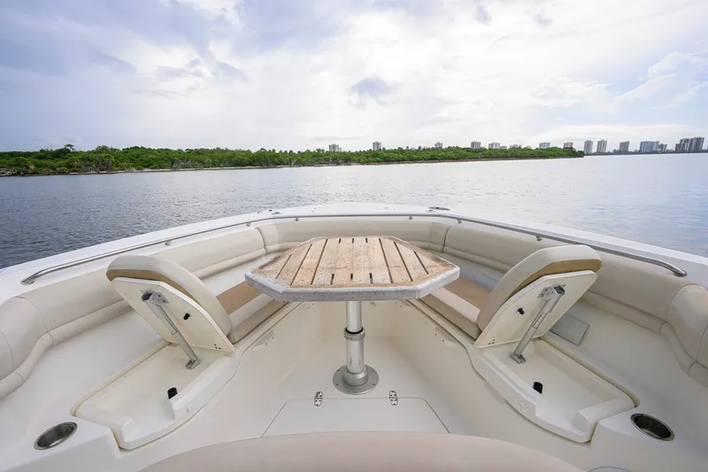 Slide: The Image of 2018 Boston Whaler 380 Outrage boat interior with seating and table, overlooking calm waters. - 3