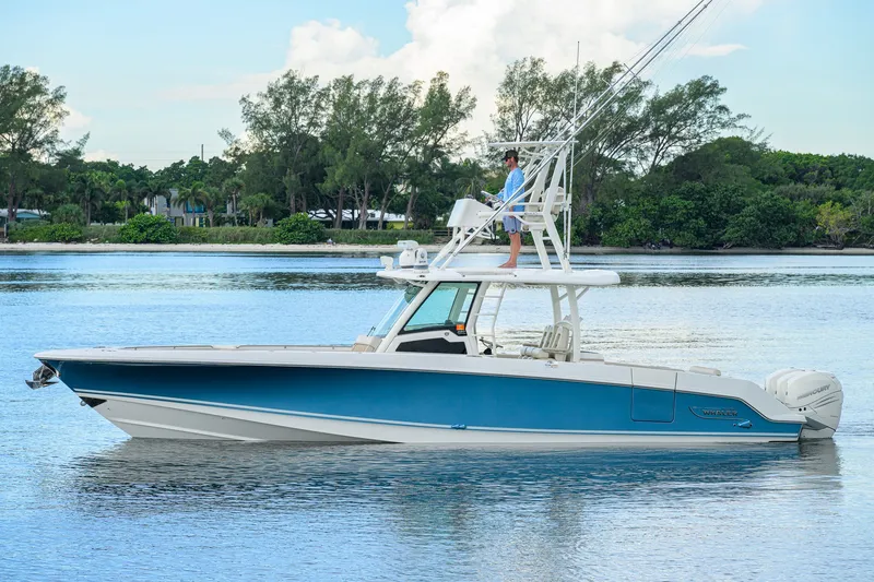 Slide: The Image of 2018 Boston Whaler 380 Outrage boat on calm water, with lush greenery in the background. - 0