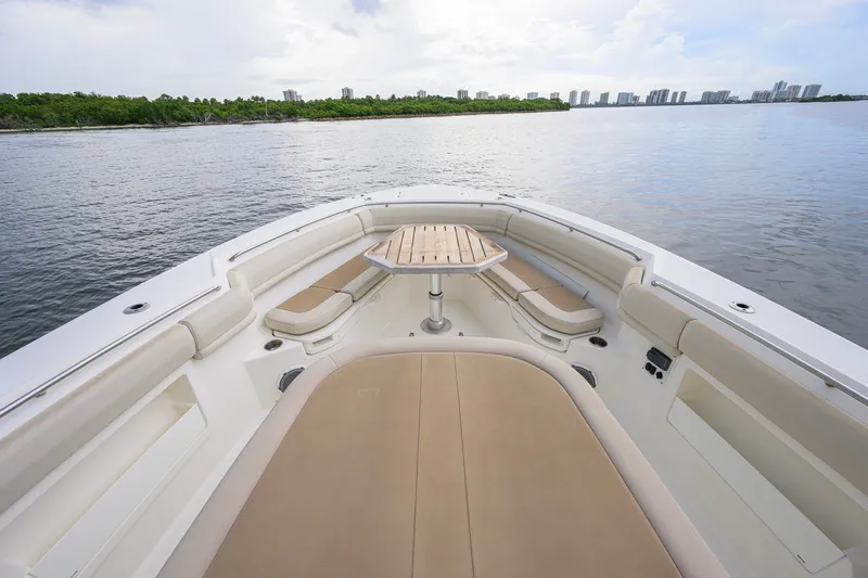 Slide: The Image of 2018 Boston Whaler 380 Outrage boat interior with seating and table, overlooking calm waters. - 22