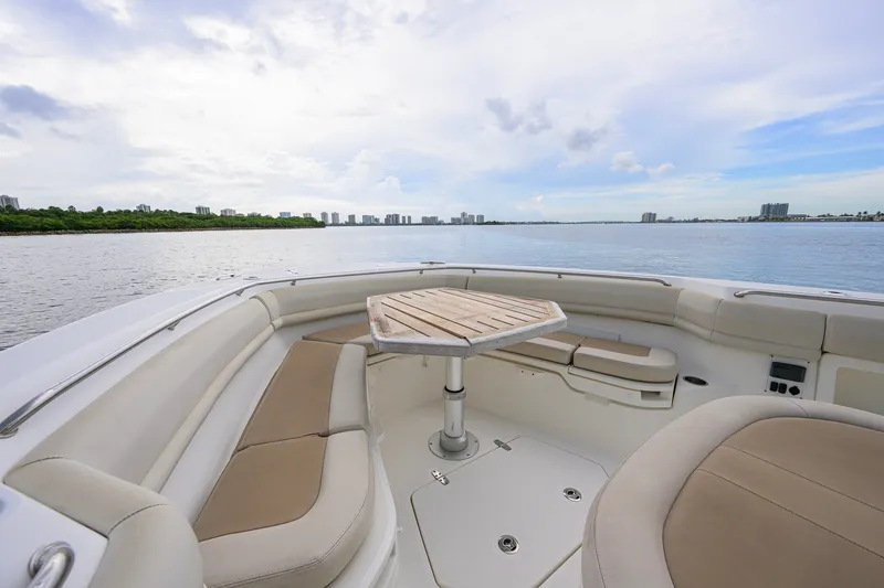 Slide: The Image of 2018 Boston Whaler 380 Outrage boat interior with seating and table, overlooking calm waters. - 19