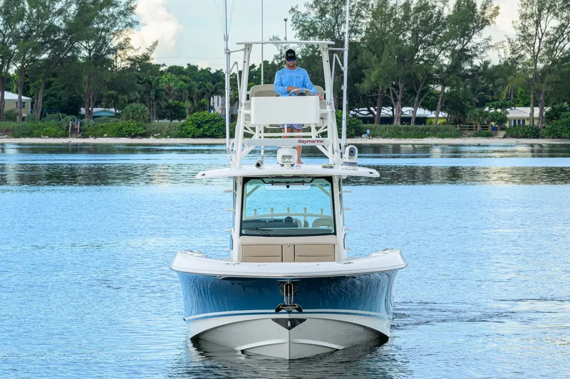 Slide: The Image of 2018 Boston Whaler 380 Outrage boat on calm water, with lush greenery in the background. - 10