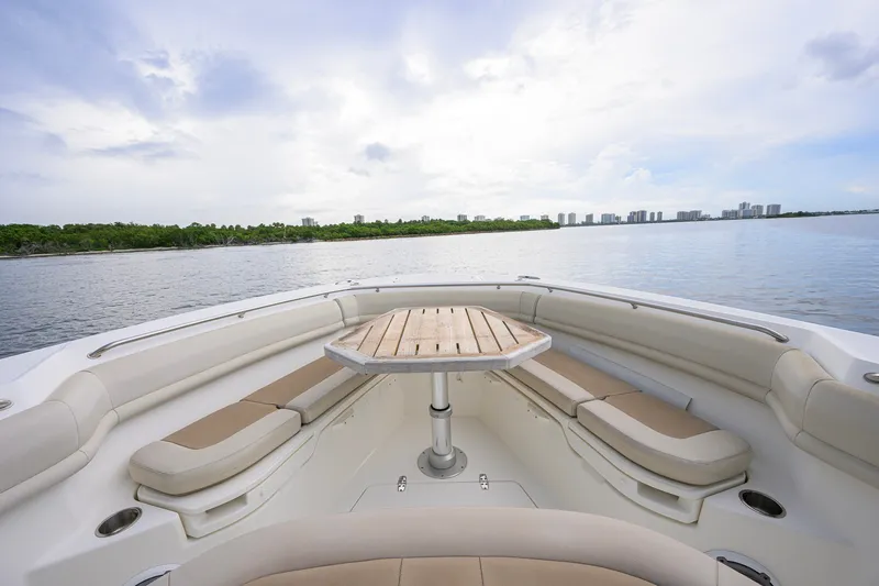 Slide: The Image of 2018 Boston Whaler 380 Outrage boat interior with seating and table, overlooking calm waters. - 21