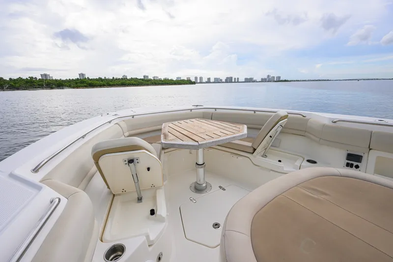 Slide: The Image of 2018 Boston Whaler 380 Outrage boat interior with seating and table, overlooking calm waters. - 20