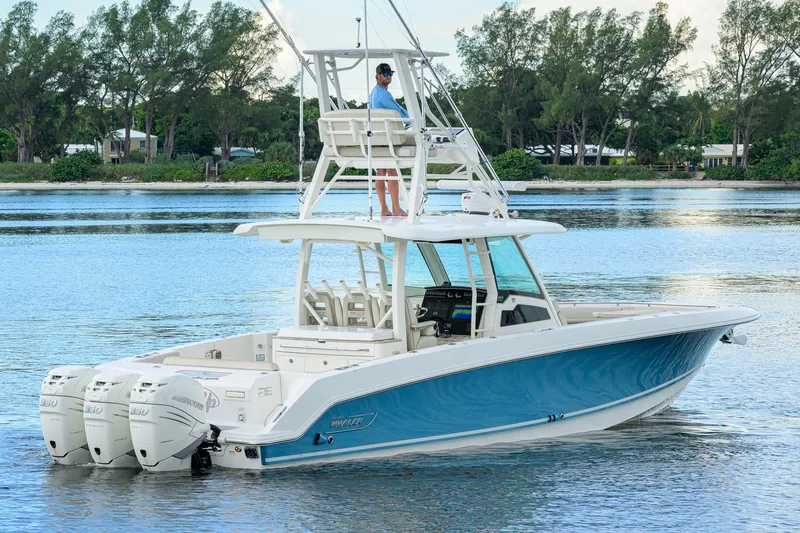 Slide: The Image of 2018 Boston Whaler 380 Outrage boat on calm water with lush green shoreline. - 7