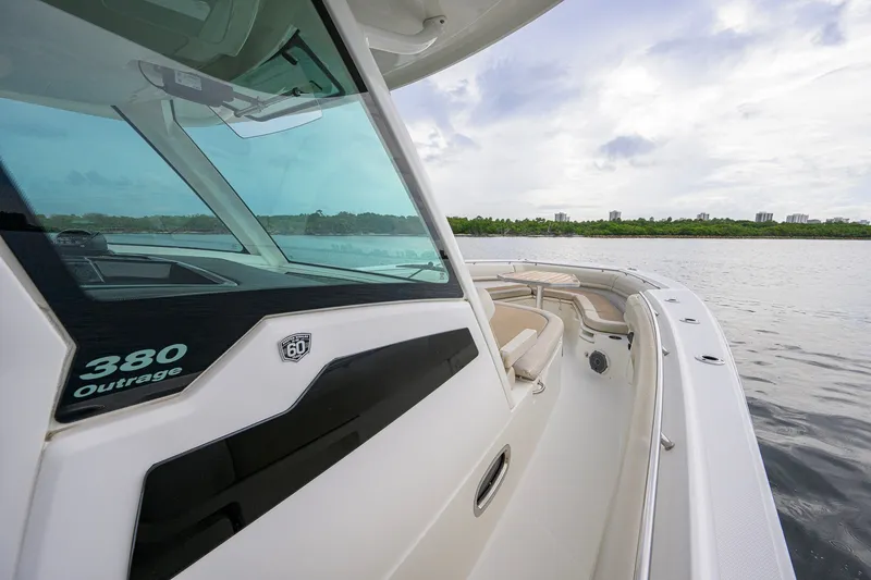 Slide: The Image of 2018 Boston Whaler 380 Outrage boat on calm water, showcasing sleek design and spacious deck. - 30
