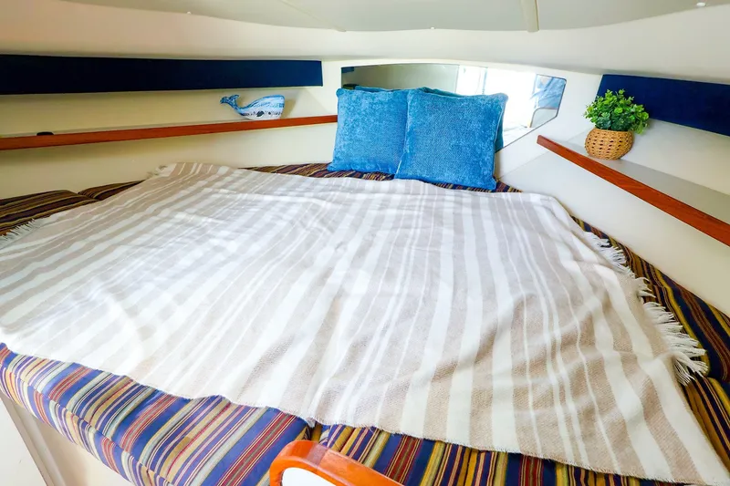Slide: The Image of Cozy cabin interior of 2003 Tiara Yachts 2900 Coronet with striped bedding and blue pillows. - 34