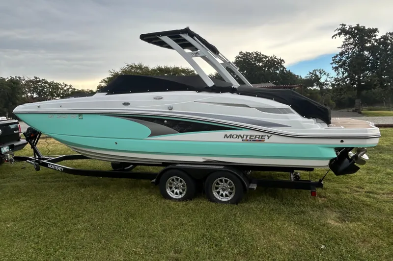 Slide: The Image of 2023 Monterey M6 boat on trailer, parked on grass under cloudy sky. - 1