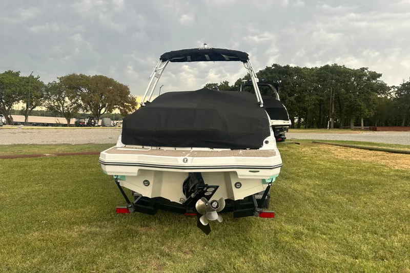 Slide: The Image of 2023 Monterey M6 boat with cover, parked on grass under cloudy sky. - 4