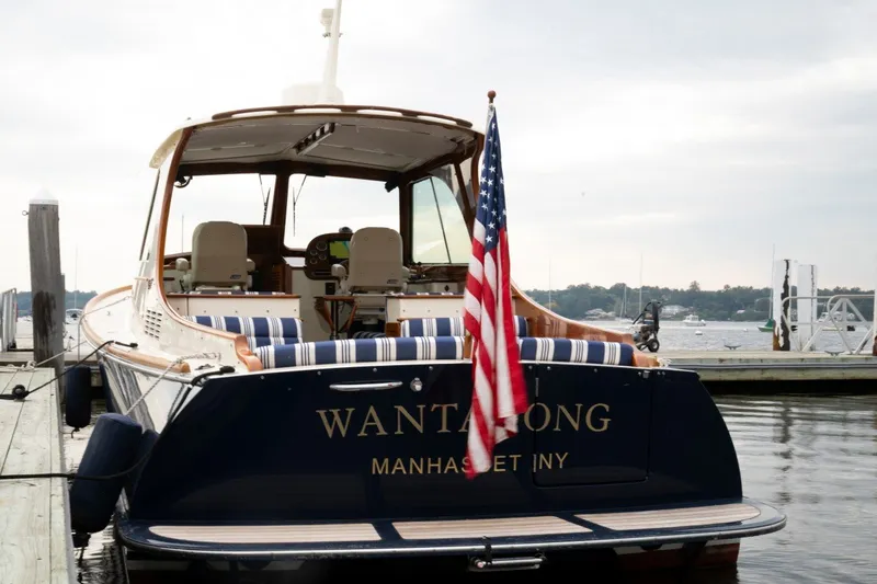 Slide: The Image of 2009 Hinckley Picnic Boat 37 MKIII docked, displaying American flag, with scenic waterfront backdrop. - 27