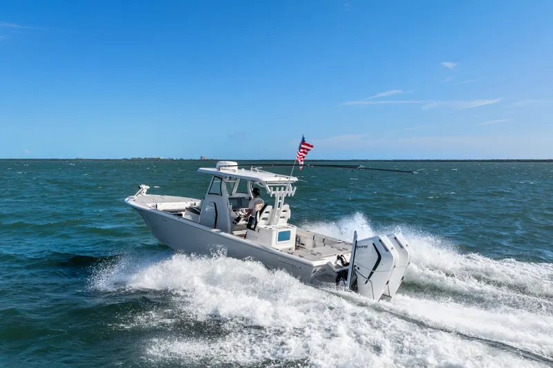 Slide: The Image of 2024 Tidewater 3100 Carolina Bay boat cruising on open water under clear blue sky. - 23