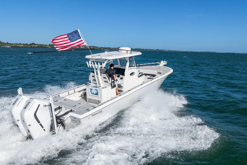 Slide: The Image of 2024 Tidewater 3100 Carolina Bay boat cruising with American flag on open water. - 24