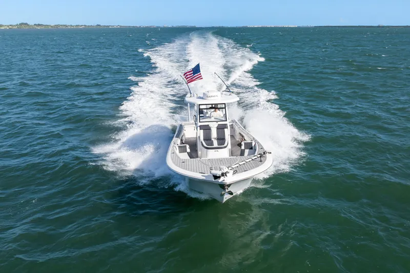 Slide: The Image of 2024 Tidewater 3100 Carolina Bay boat cruising on open water with American flag. - 20