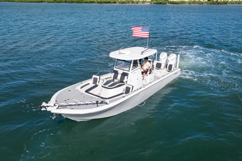 Slide: The Image of 2024 Tidewater 3100 Carolina Bay boat cruising on open water with American flag. - 2