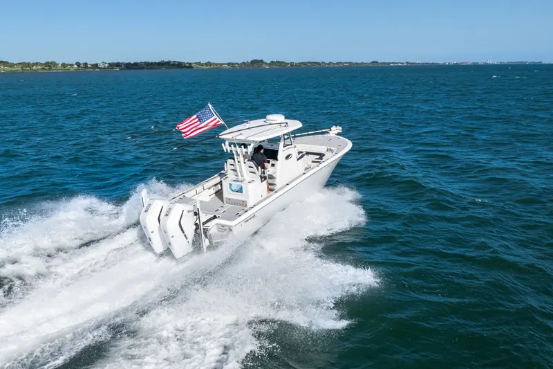 Slide: The Image of 2024 Tidewater 3100 Carolina Bay boat cruising on open water with American flag. - 25