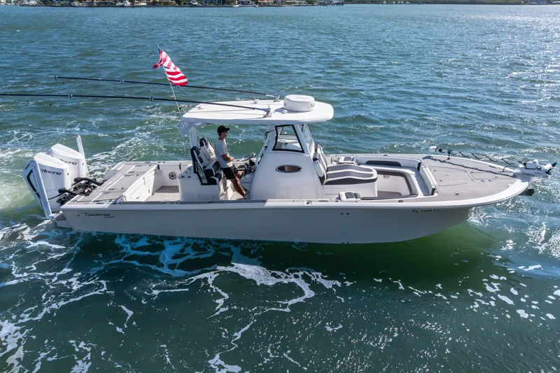 Slide: The Image of 2024 Tidewater 3100 Carolina Bay boat cruising on open water with American flag. - 0