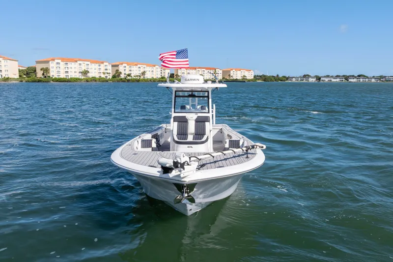 Slide: The Image of 2024 Tidewater 3100 Carolina Bay boat on water with American flag, clear sky background. - 6