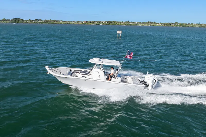Slide: The Image of 2024 Tidewater 3100 Carolina Bay boat cruising on open water with American flag. - 19