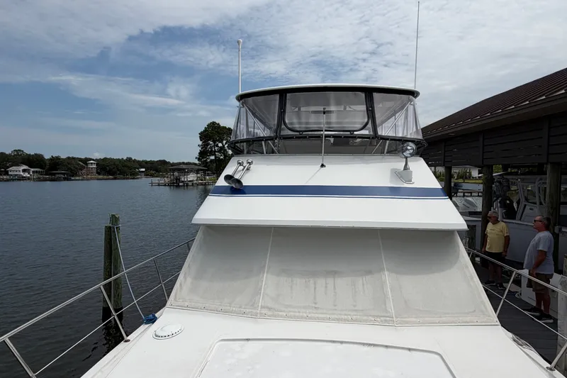 Slide: The Image of 1989 Chris-Craft 427 Catalina yacht docked by a serene waterfront. - 10