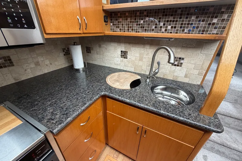 Slide: The Image of 1989 Chris-Craft 427 Catalina kitchen with granite countertop, stainless steel sink, and wooden cabinetry. - 35