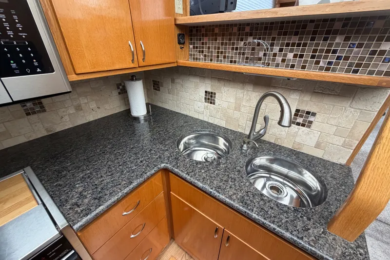 Slide: The Image of 1989 Chris-Craft 427 Catalina kitchen with granite countertops, dual sinks, and wooden cabinetry. - 36