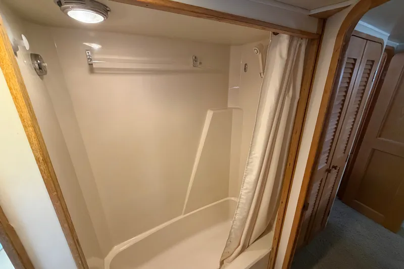 Slide: The Image of Shower area inside 1989 Chris-Craft 427 Catalina yacht, featuring curtain and wooden accents. - 60