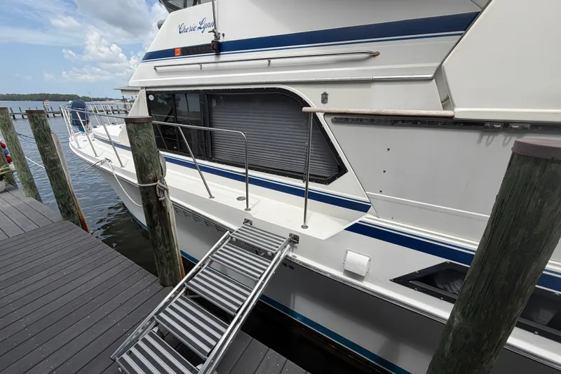 Slide: The Image of 1989 Chris-Craft 427 Catalina yacht docked with boarding ladder, featuring sleek white and blue design. - 8