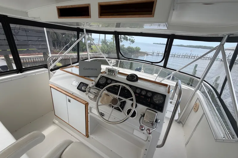 Slide: The Image of 1989 Chris-Craft 427 Catalina helm with Garmin navigation, overlooking serene waterfront view. - 16