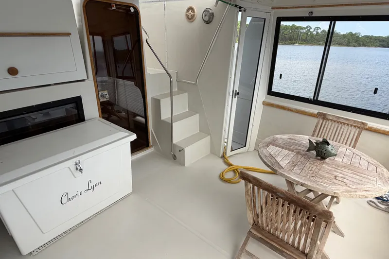 Slide: The Image of 1989 Chris-Craft 427 Catalina interior with wooden table, chairs, and lake view. - 11